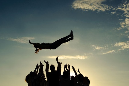 Group throwing girl in air (silhouette)