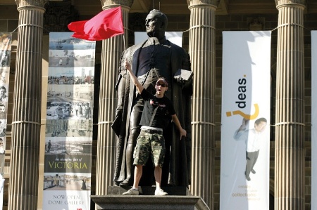 Man with flag standing by statue