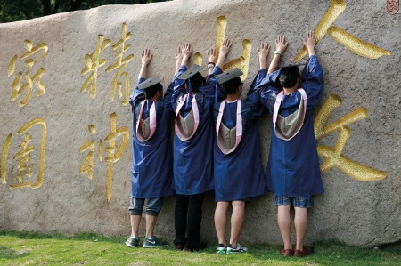 Chinese graduates leaning on wall