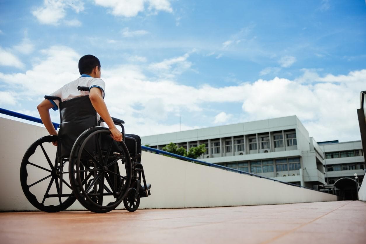 A young man in a wheelchair heading towards a university building