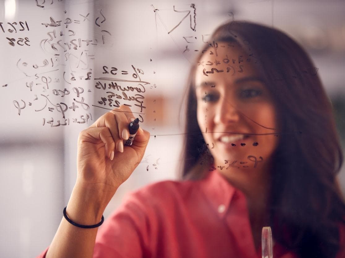 A woman writing out equations on a glass screen