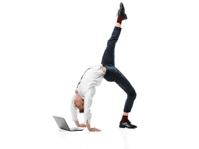 Man doing a back bend while looking at laptop