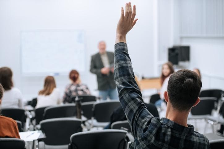 A student raising a hand with a question in class