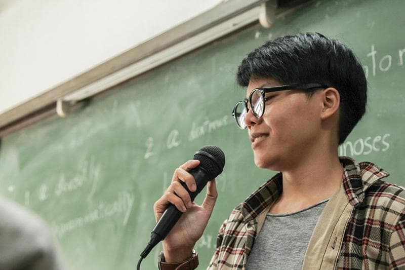 Asian student addressing class with microphone