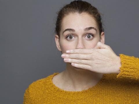 20-something woman with hand over mouth illustrating article about addressing taboo subjects