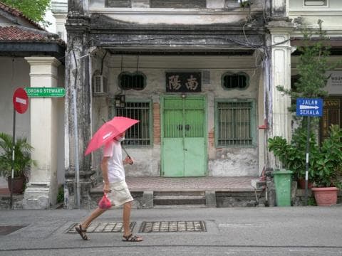 A man walks past a colonial-era building in modern-day Malaysia