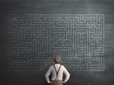 Man staring at a maze on a blackboard
