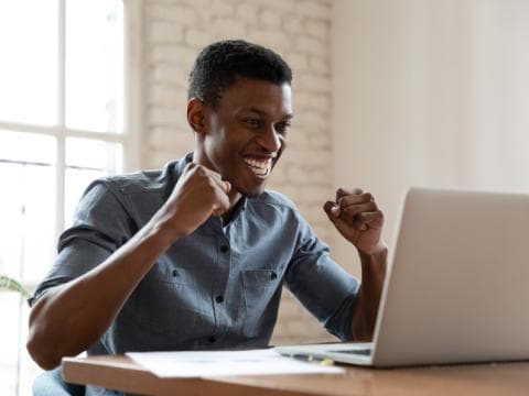 Black male student happy looking at laptop