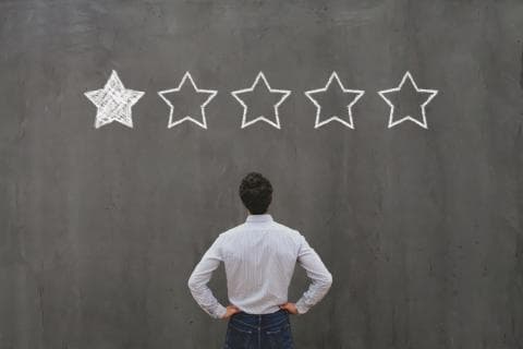 A man staring up at a board with a one star rating displayed