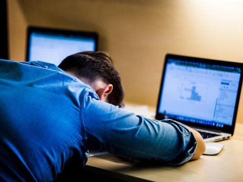 Depressed student hiding face on arms in front of laptop