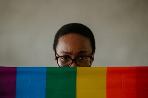 Black woman holding an LGBTQ+ flag