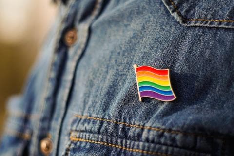 Person wearing an LGBTQ+ rainbow badge