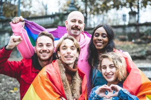 LGBTQ+ campaigners pose with the rainbow flag