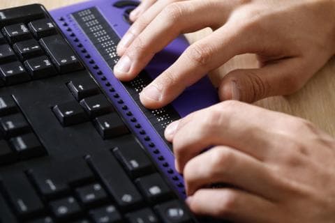Hands typing on a Braille keyboard