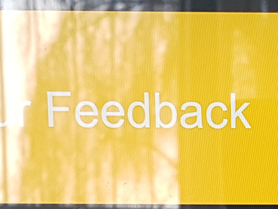 “Feedback” appears in white text with a yellow background, with a contrast ratio of 1.7:1. The image has a reflection of an open window on it, making the text much harder to read. In some places the contrast of the text is as low as 1.0001:1