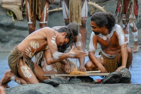 Indigenous Australian people perform a ritual of lighting a fire