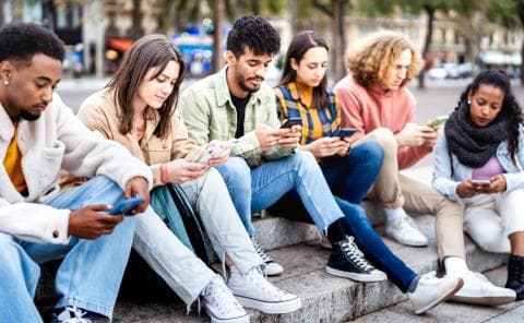 A group of Gen Z students gaze at their phones 