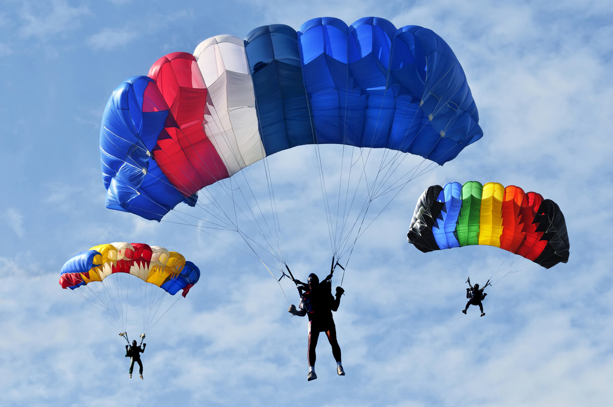 Three parachute jumpers floating to land