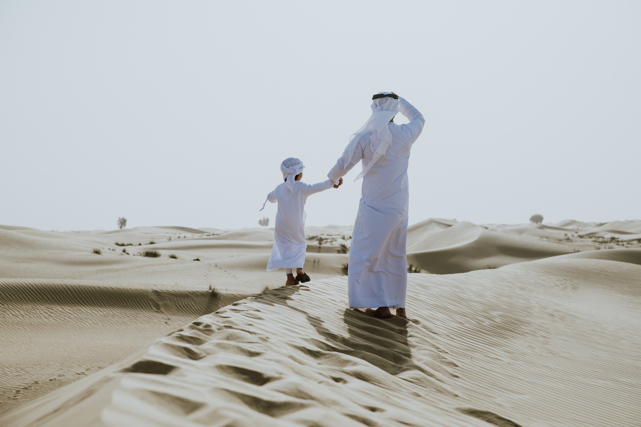 Father and son walking in the UAE sand dunes