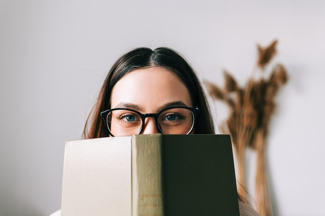 Student peers over the top of a book