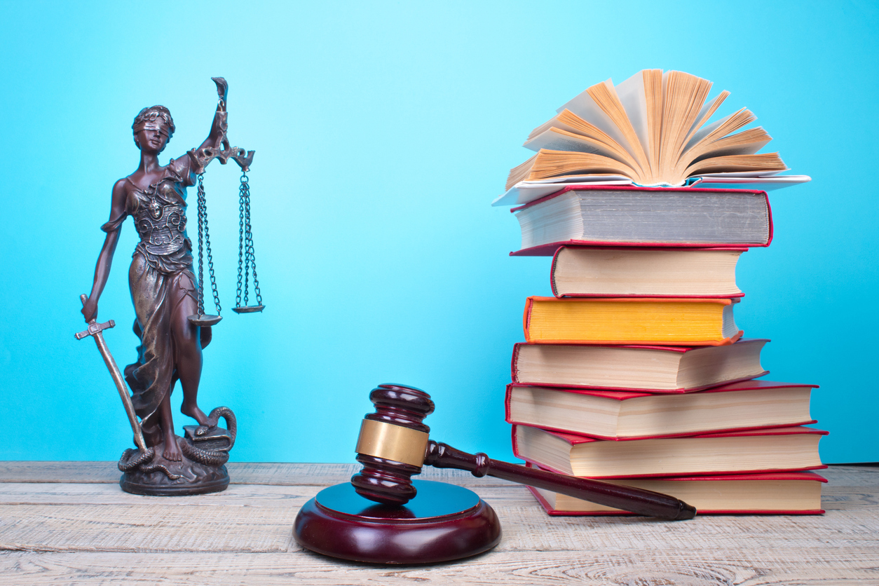 Statue of blind justice, gavel and pile of text books