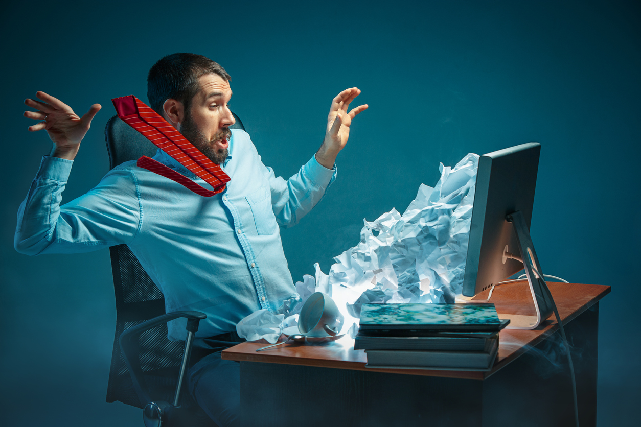 Man overwhelmed by the amount of paper emerging from his computer screen