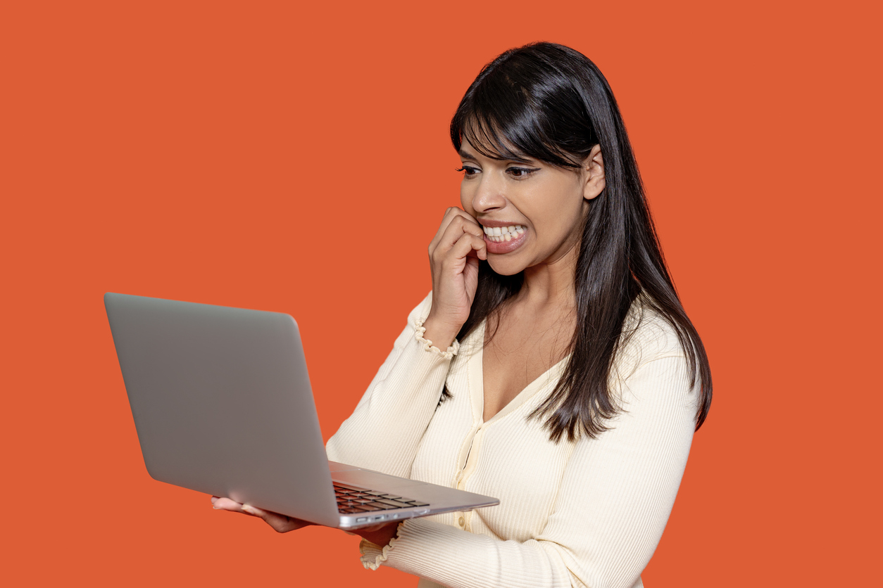 Woman looking at laptop with teeth clenched