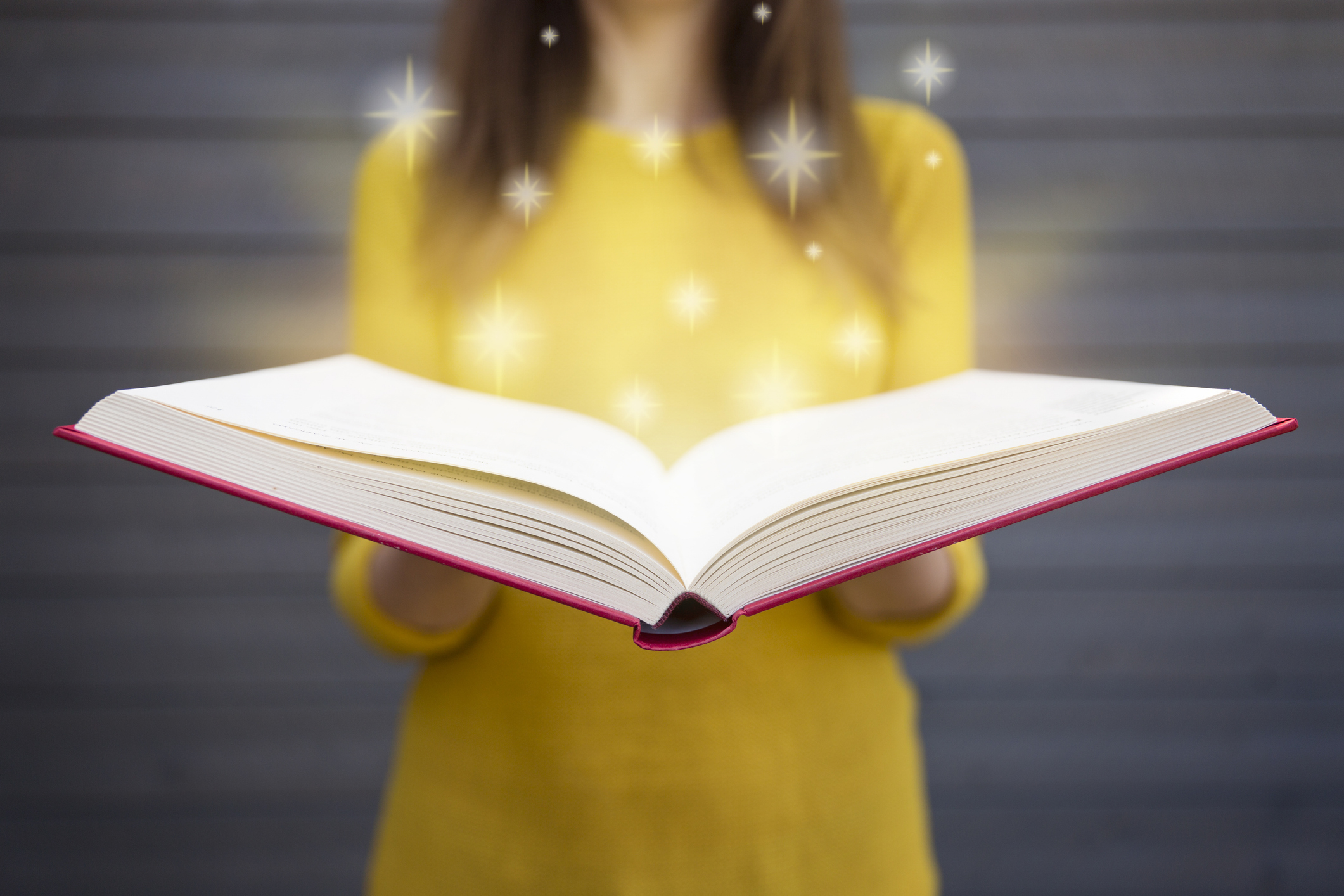 Student holding open blank book, from which stars emerge