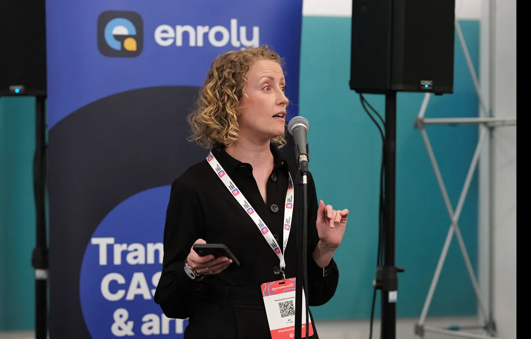 Speaker addressing attendees in front of an enrolu sponsor banner at a Times Higher Education event