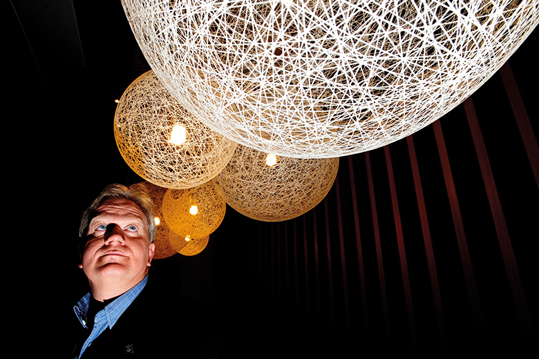 Nobel laureate Brian Schmidt looking up at lit up spheres