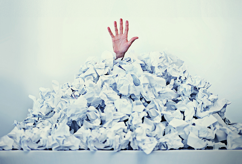 Hand sticking out of a mound of crumpled paper