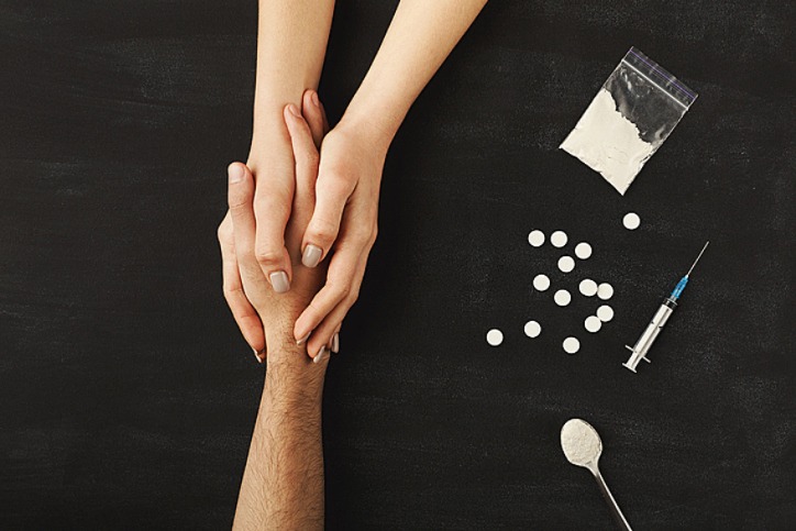 Hands held on a table of drugs, illustrating drug recovery support
