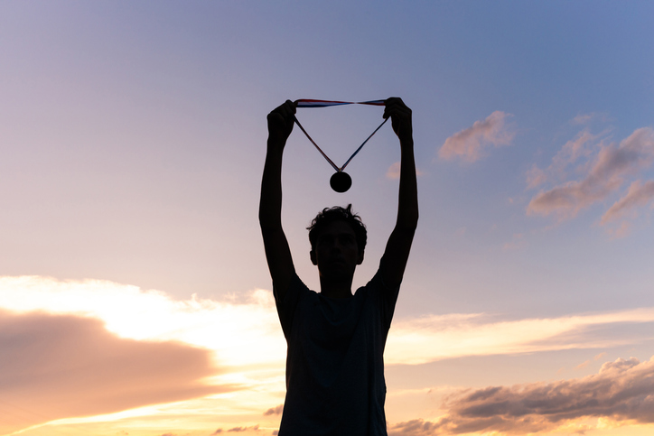 An athlete holds up their medal, illustratiung TEF ratings