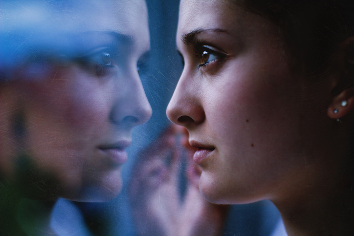 A woman stares at herself in the mirror, illustrating universities' role in shaping national identity