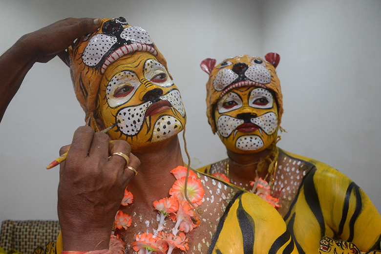 Indian dancers apply tiger face paint, as an illustration of credibility problems in India's universities.