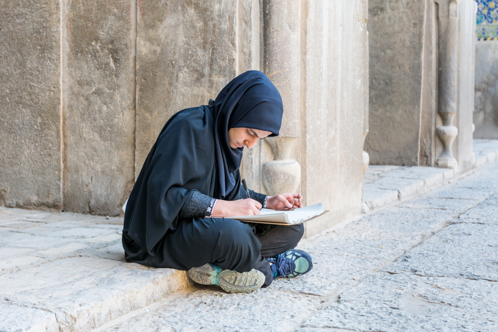 An Iranian student sits on the ground, illustrating inequliaty in university entrance