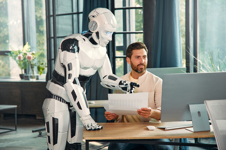 A robot helps a man write something, illustrating AI augmentation