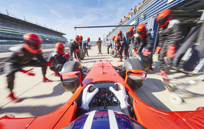 Technicians change the tyres of a racing car, symbolising support for spinouts