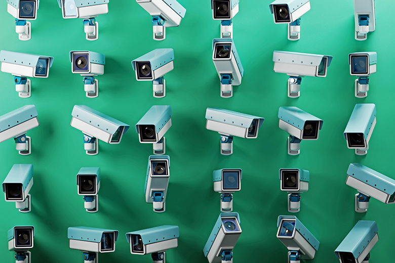 An array of multiple security cameras mounted on a green wall, symbolising surveillance, security, and monitoring. To illustrate that franchise partners must be helped to improve, not just monitored.