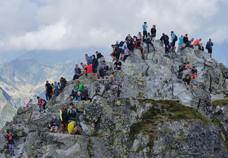 Crowd of tourists, hikers, on the narrow and rocky Rysy Peak (2500m), the highest peak in Poland to illustrate Success recast as failure