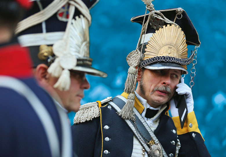 An actor in the role of a soldier in the 7th Polish Lancer Regiment talks on a mobile phone upon his arrival for the opening ceremony to commemorate the 200th anniversary of The Battle of Nations