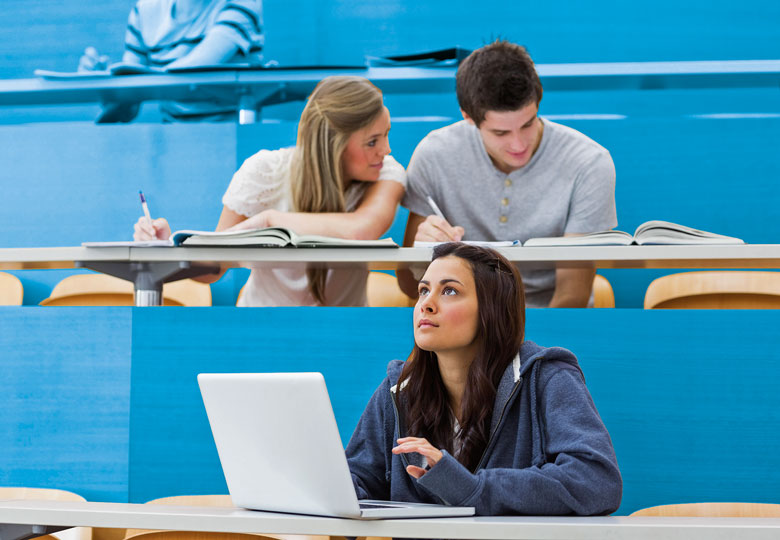 Students sitting in lecture with girl thinking at laptop