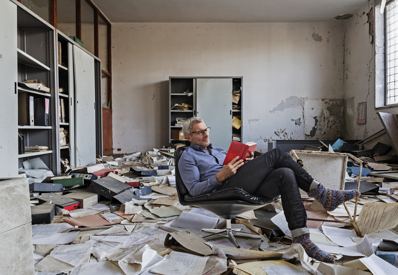 Montage of a person sitting reading in an Abandoned office with many papers on the floor