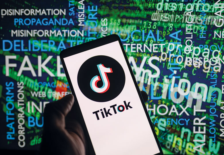 TikTok icon logo displayed on a smartphone with disinformation on screen in the background to illustrate Students are ‘learning’ about Israel-Hamas from TikTok. We must step up