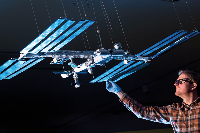 A technician with a Lego model of the International Space Station to illustrate 'Does business logic mean that we should break up universities?'