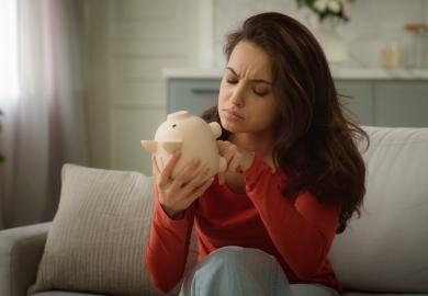 Woman tries to find coins in her empty piggy bank