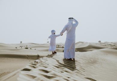 Father and son walking in the UAE sand dunes