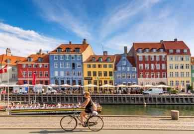 Colourful houses in Copenhagen, with woman cycling past