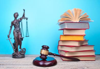 Statue of blind justice, gavel and pile of text books