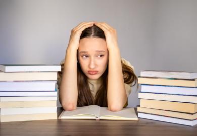 Student, surrounded by books and brochures, looking stressed
